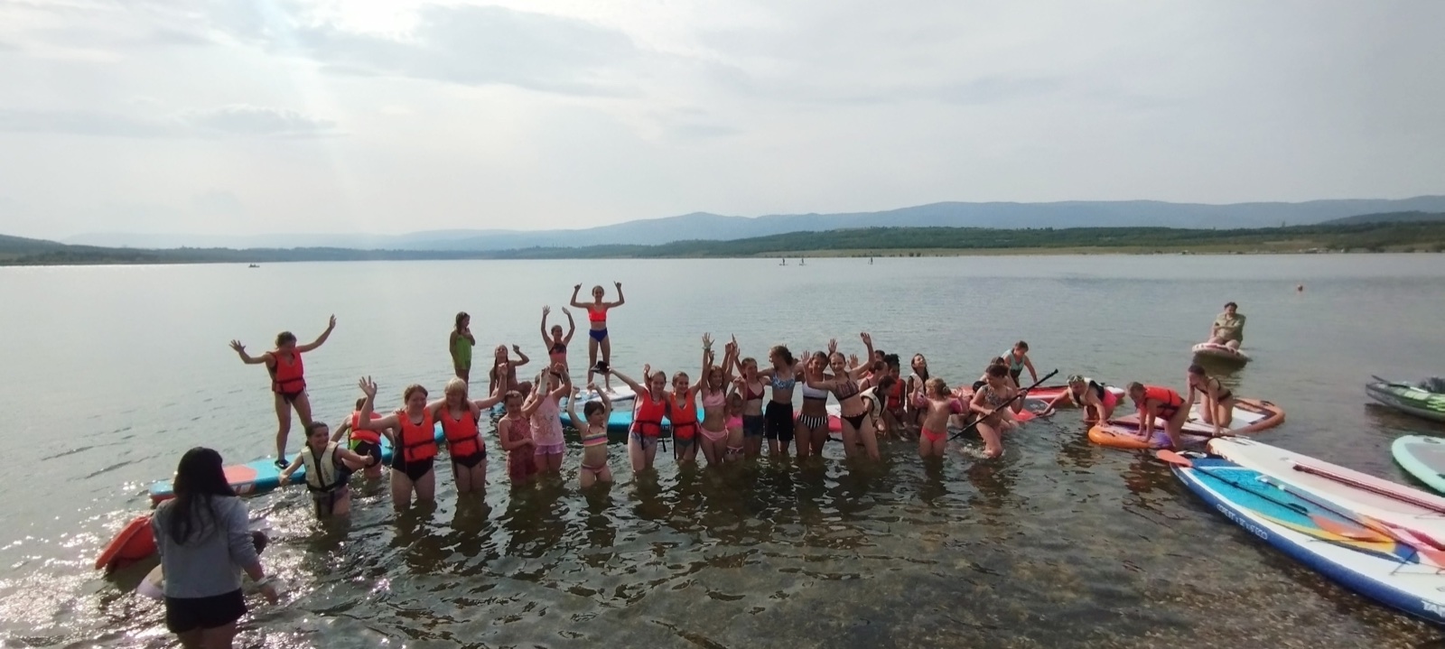 Skupina dětí a paddleboardy u jezera Milada